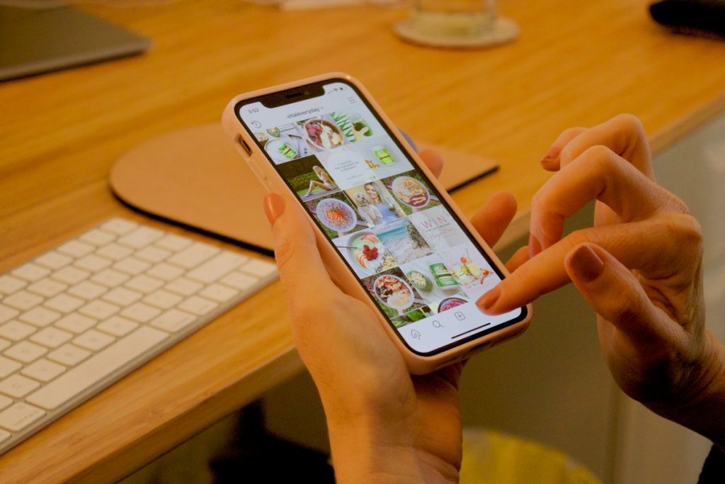 Hand met smartphone aan een bureau