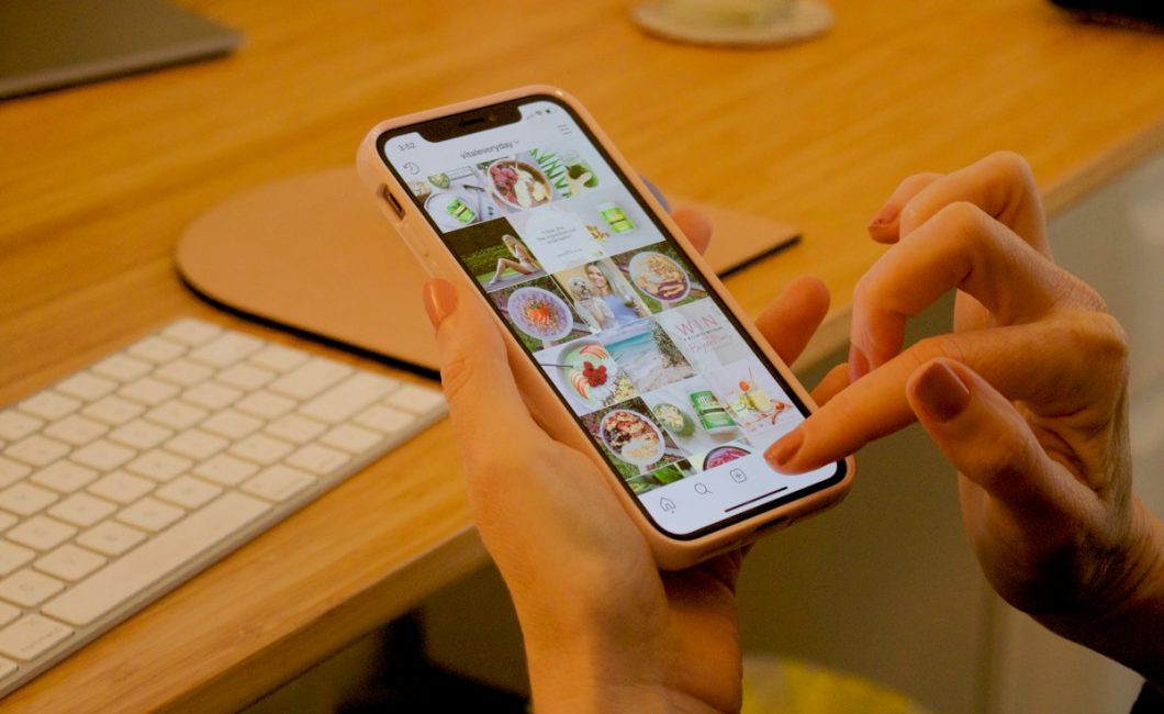 Hand met smartphone aan een bureau