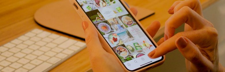 Hand met smartphone aan een bureau
